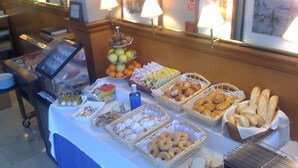 Una mesa de buffet con diversos alimentos, incluyendo frutas, pasteles y pan.
