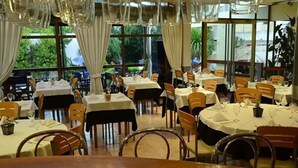 A restaurant with multiple tables and chairs, large windows, and a view of greenery outside. - Ñikén Hotel & Spa (Necochea)