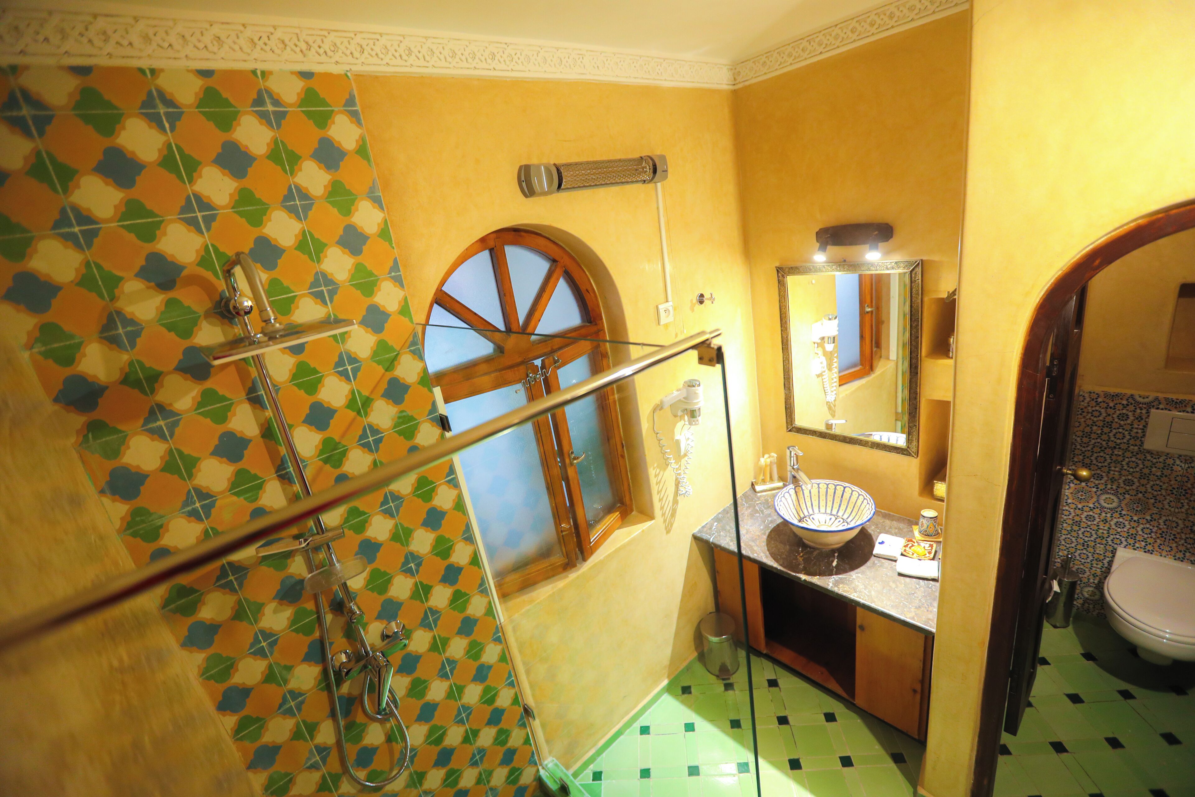 A bathroom with a tiled floor, a sink, a mirror, and a toilet.