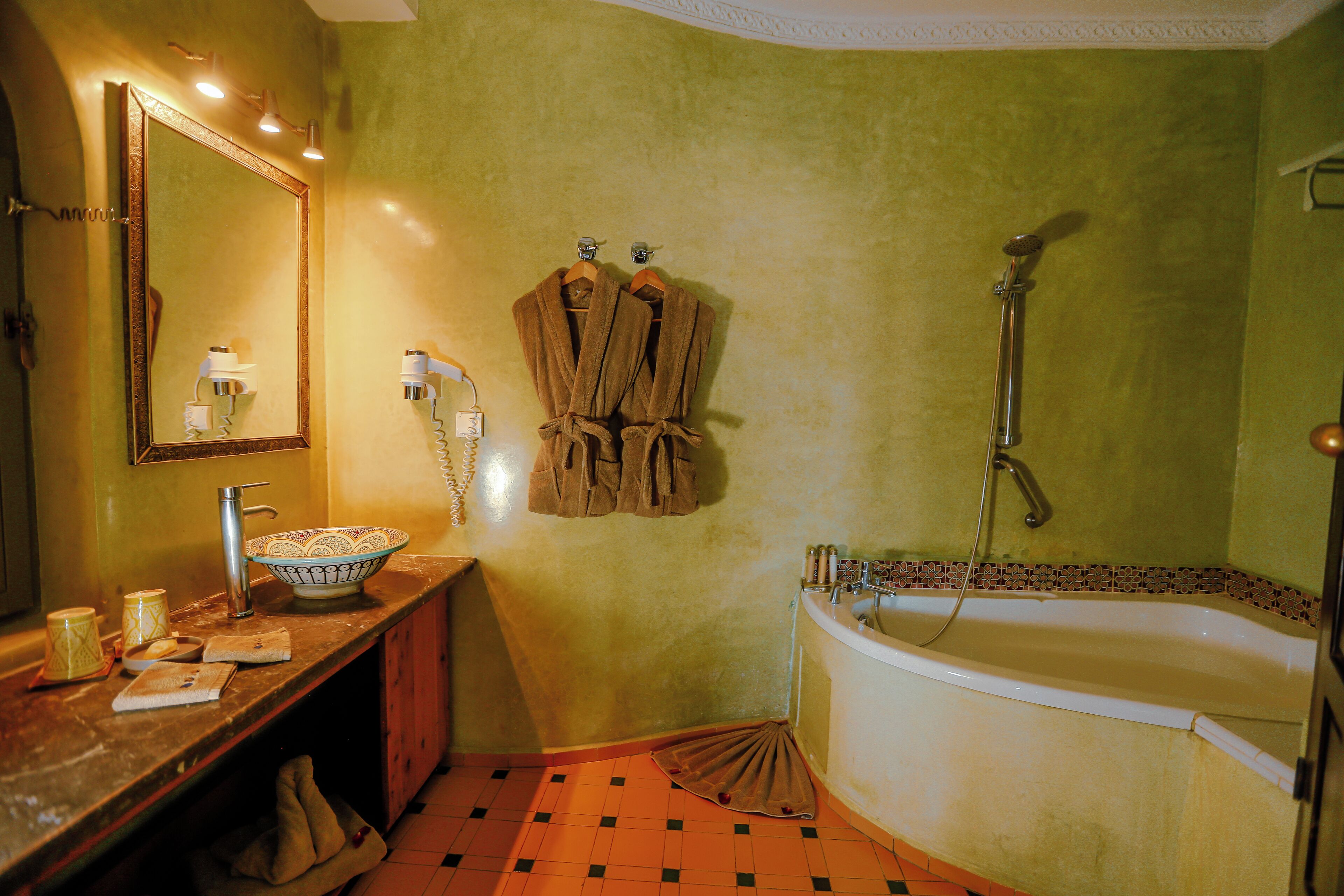 A bathroom with a bathtub, a sink with a mirror, and a towel rack with robes.