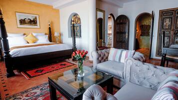 Habitación de hotel con cama, sofá, mesa de centro y un espejo decorativo.