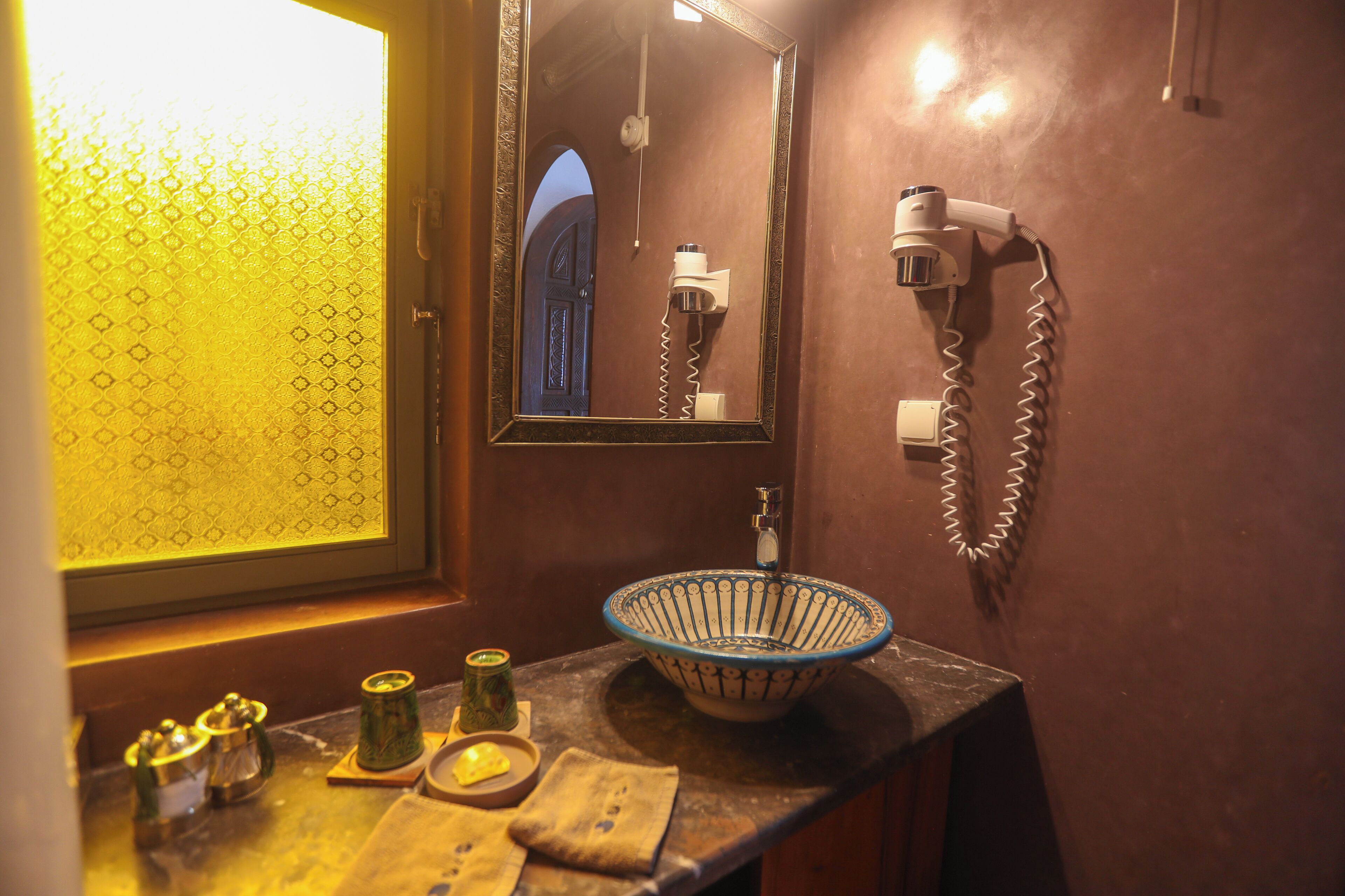 A bathroom with a sink, a mirror, and a hairdryer mounted on the wall.