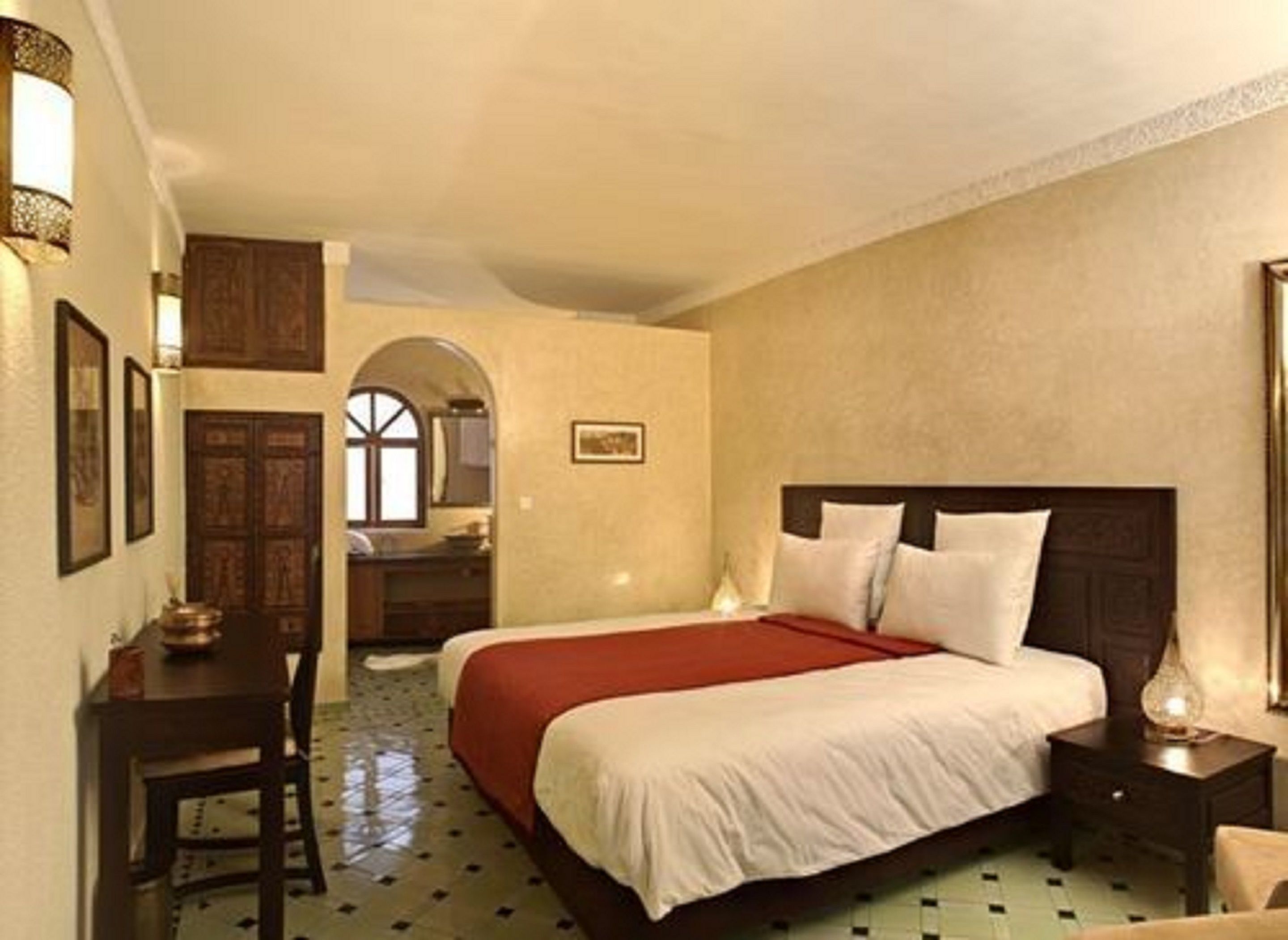 A hotel room with a large bed, a desk, and a chair.