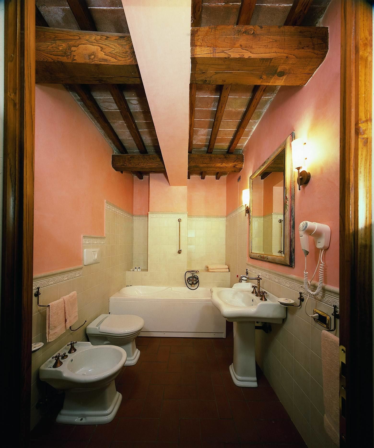 Een badkamer met een bad, twee wastafels, een toilet en een haardroger.
