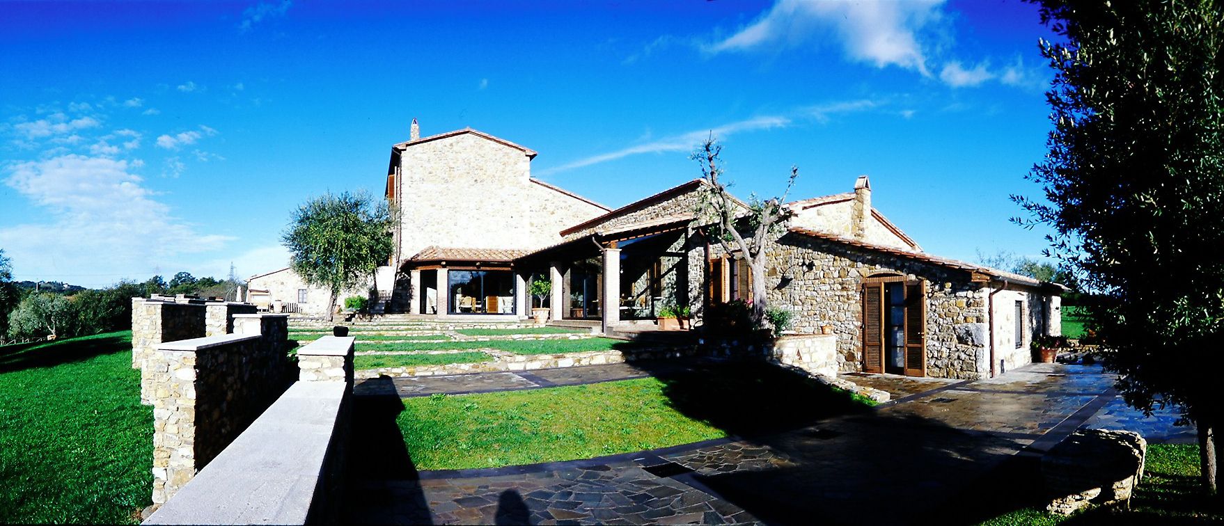 A stone building with a courtyard, a covered porch, and a stone wall.