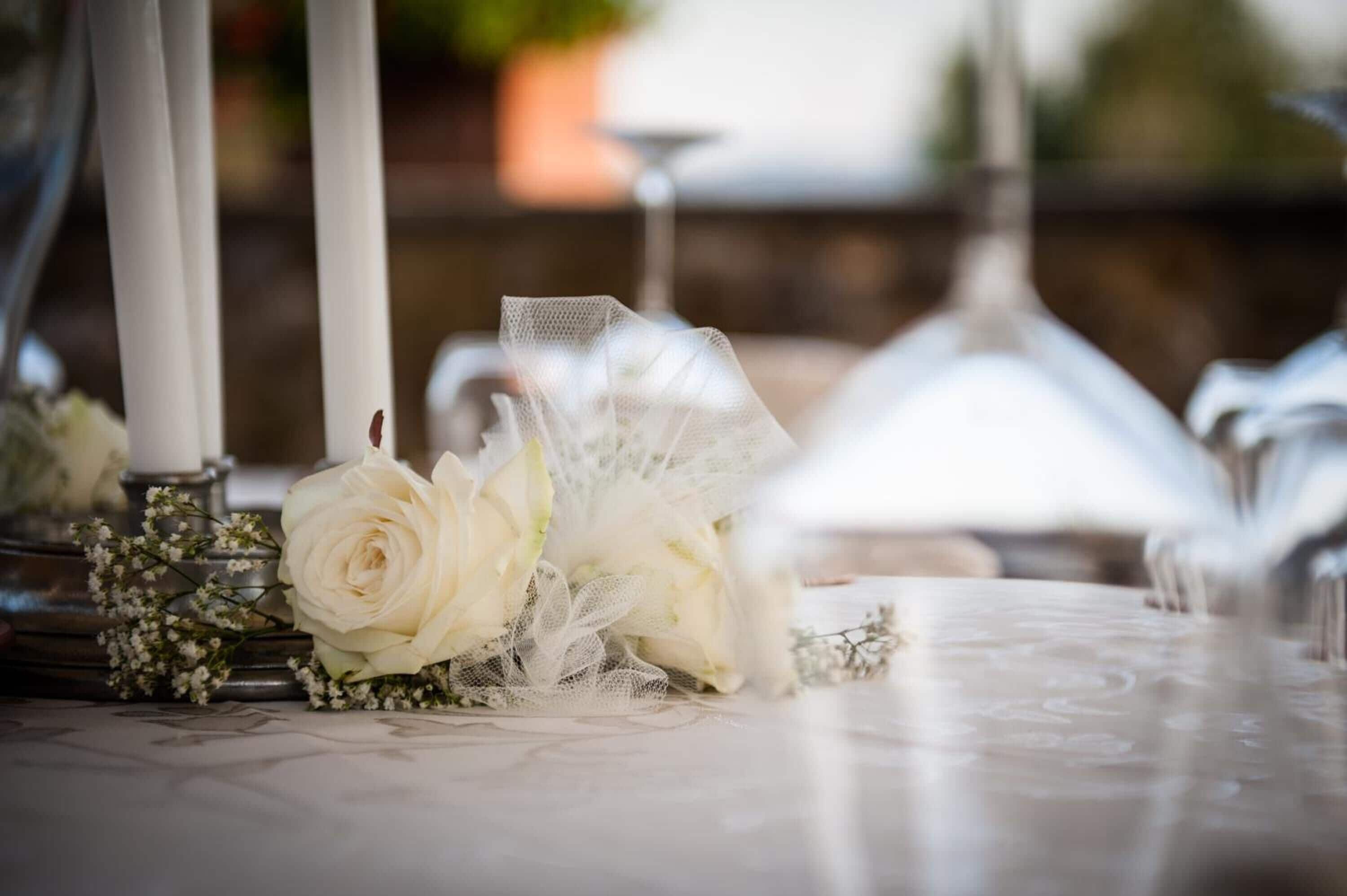 Une table ornée d’une rose blanche et de dentelle, de bougies et d’un vase en verre.