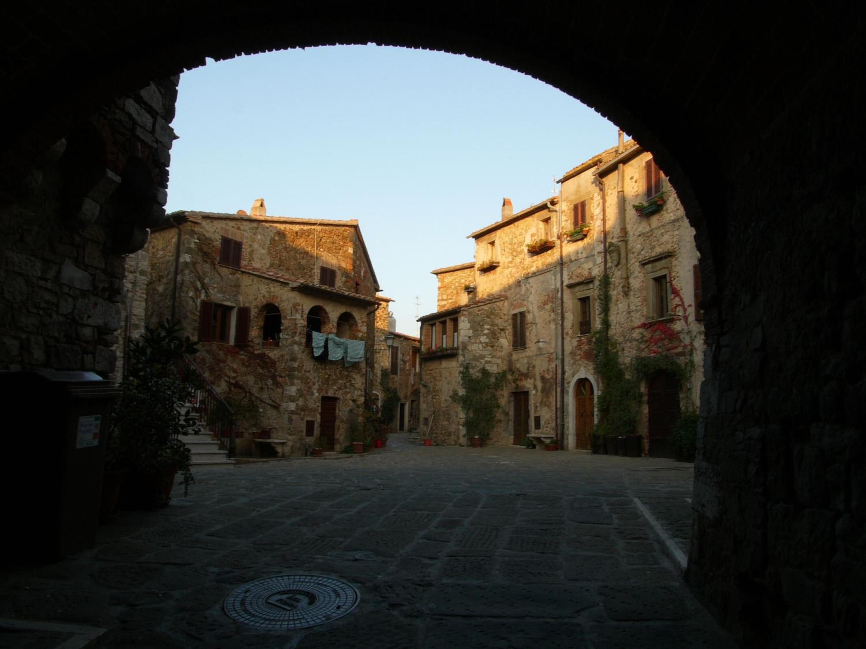 Un edificio antiguo de piedra con un patio central, un arco de entrada y arquitectura tradicional.
