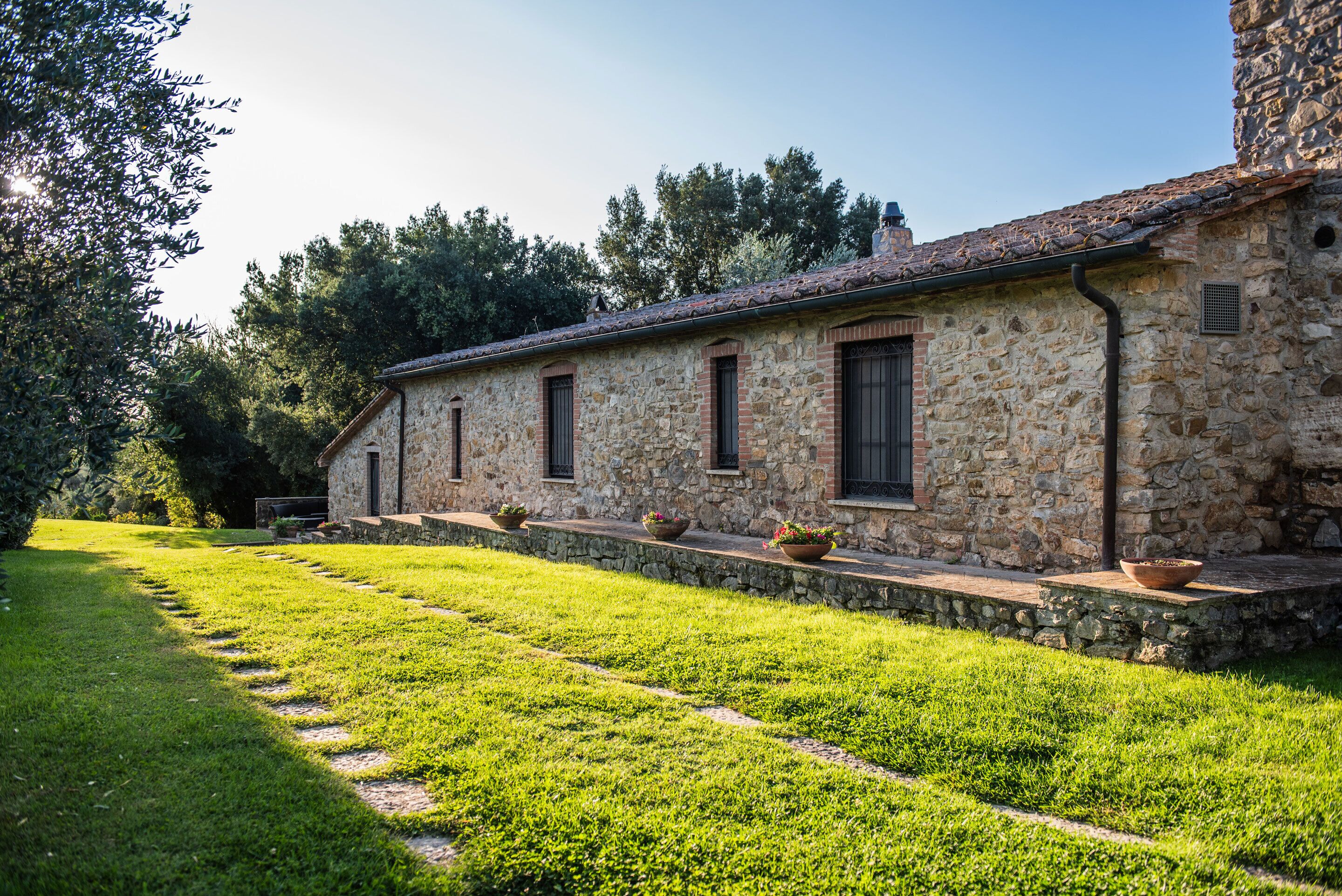 A stone building with a long, narrow porch and potted plants.