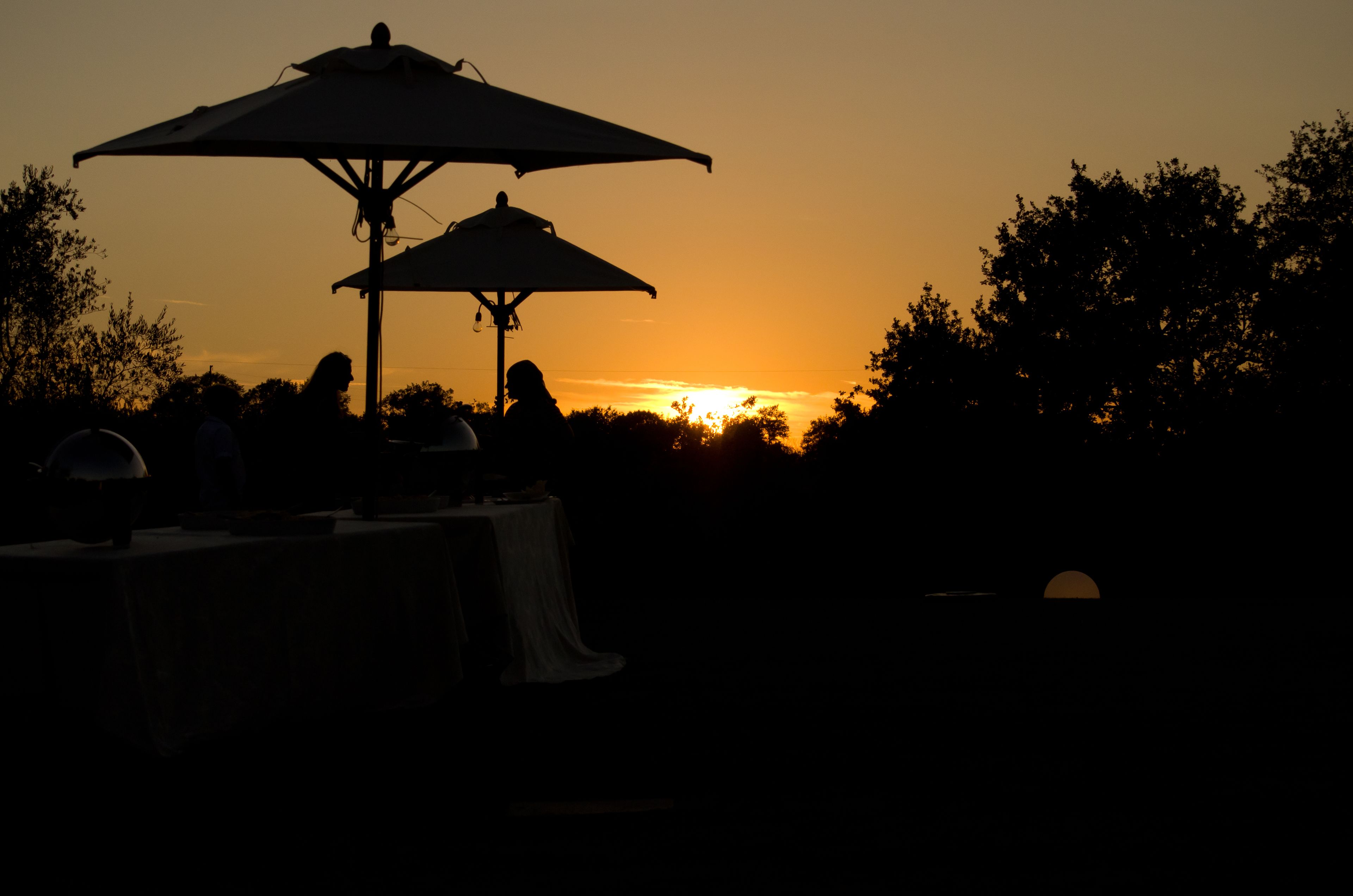 A sunset with two umbrellas and a table set up outdoors.