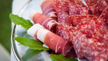 A plate of sliced cured meats with bay leaves.