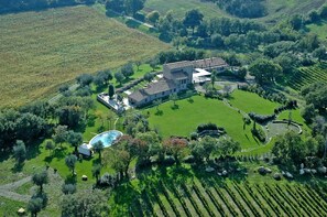 Vista aérea de una propiedad con una casa grande rodeada de campos verdes y una piscina.