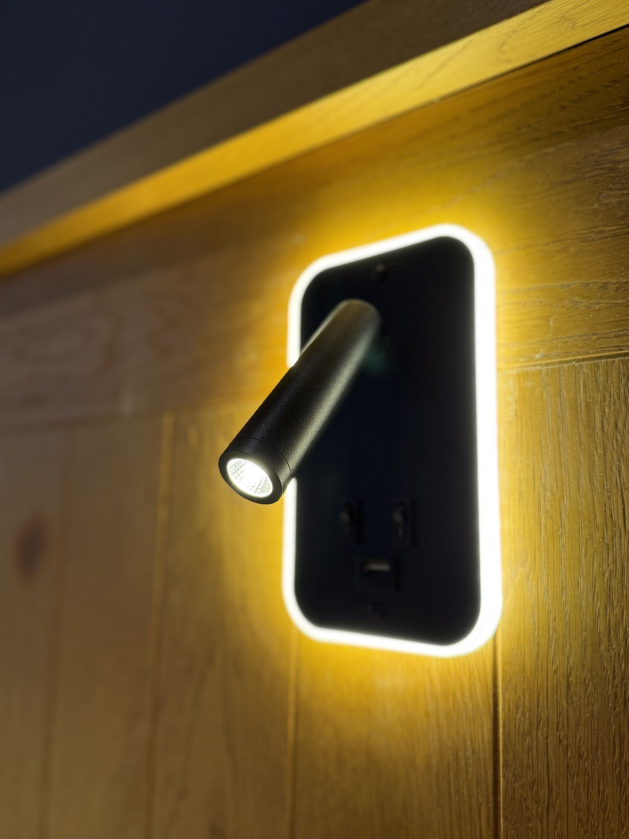 A wall-mounted light fixture with a cylindrical shape and a glowing outline.