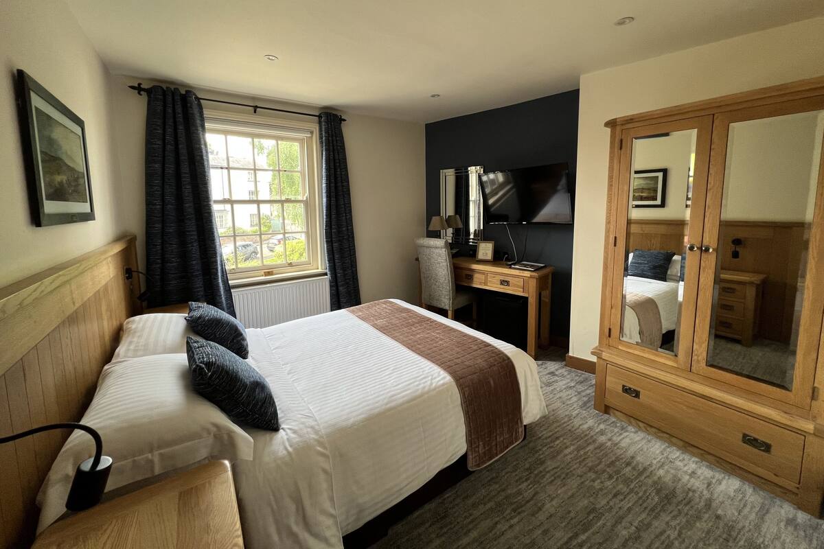 A hotel room with two beds, a desk, a TV, and a wardrobe.