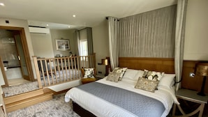 A spacious bedroom with a large bed, a wooden headboard, and a view of a balcony.
