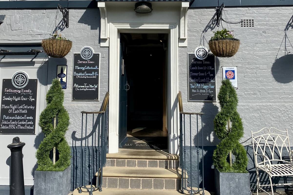 A building with a sign reading "THE STAR". There are two black metal chairs and two potted plants on the steps.