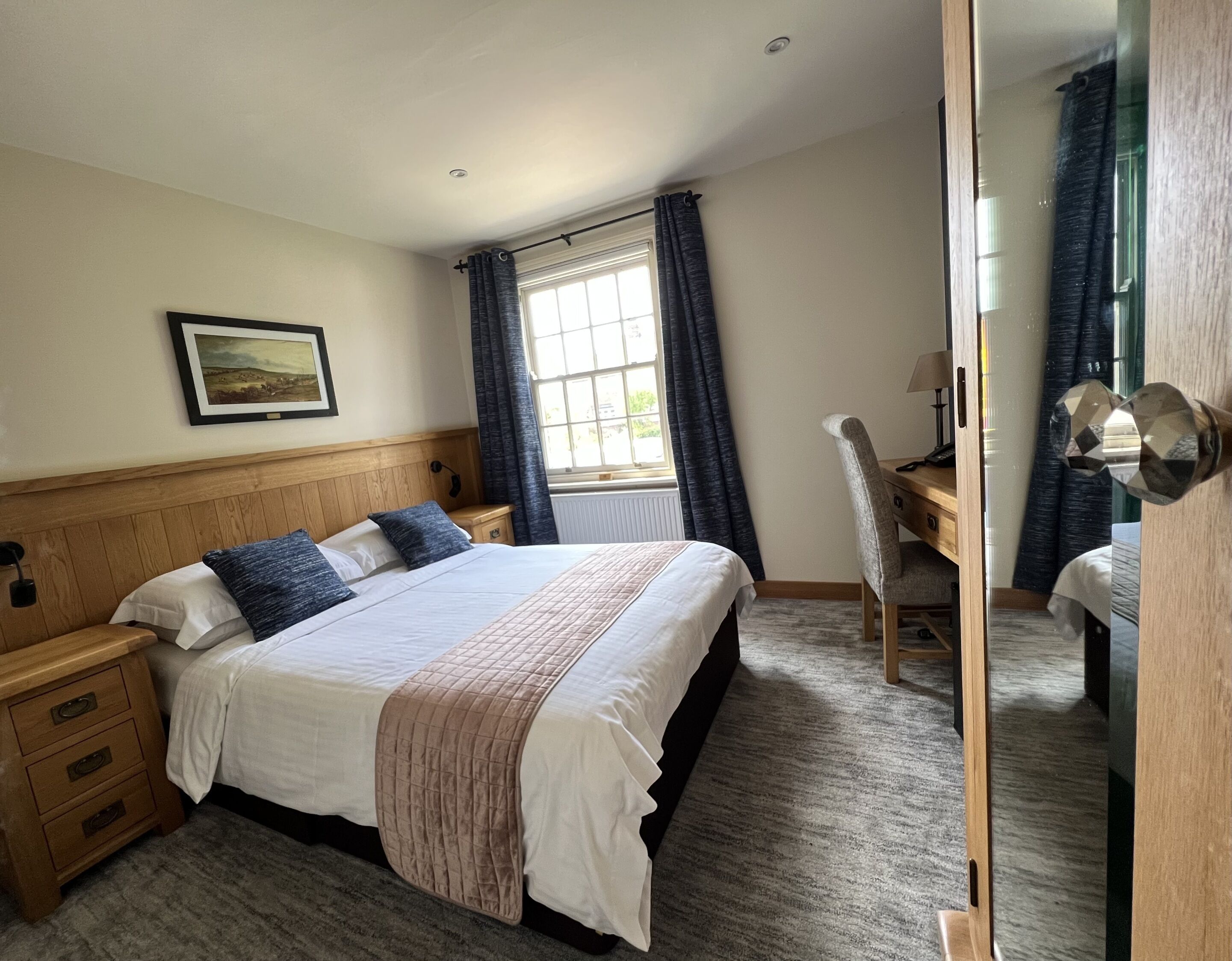 A bedroom with a bed, bedside tables, a desk, and a chair.