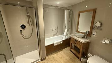 Une salle de bain moderne dotée d’une douche à parois de verre, d’une baignoire sur pieds, d’un meuble-lavabo en bois et de toilettes.