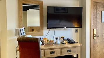 Une chambre d’hôtel avec un bureau en bois, un téléviseur à écran plat fixé au mur, un téléphone et une petite poubelle.