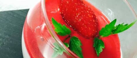 A dessert with a strawberry and mint garnish in a glass.