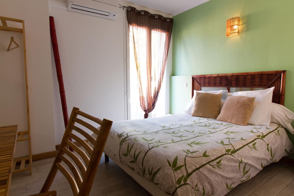 A bedroom with a bed, a wooden chair, a wardrobe, and a window with curtains.