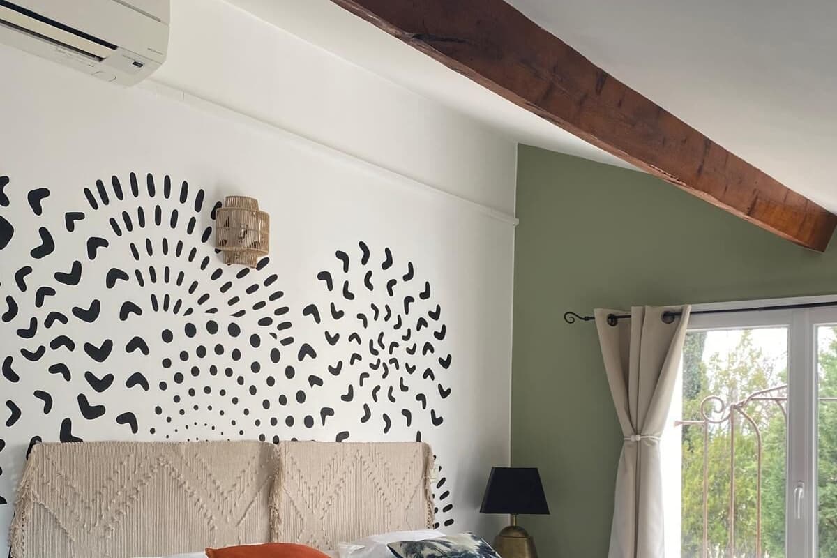 A bedroom with a bed, a nightstand, a lamp, and a window with curtains.