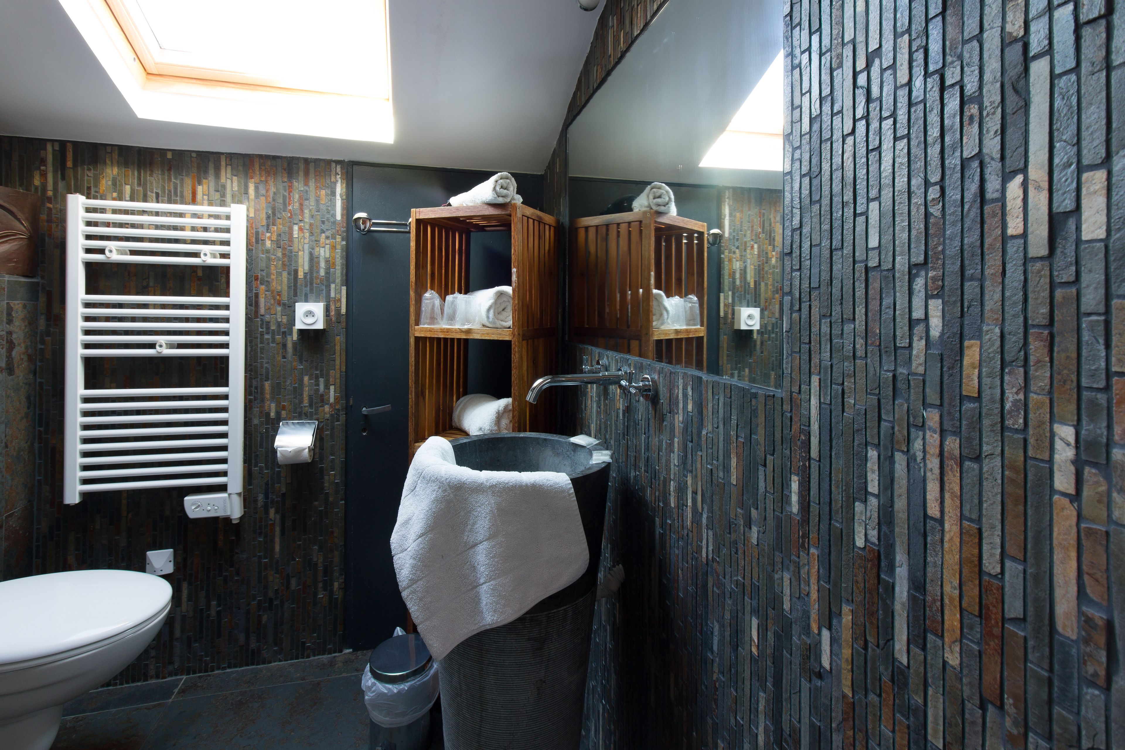A modern bathroom with a skylight, a freestanding bathtub, a towel rack, and a mirror.