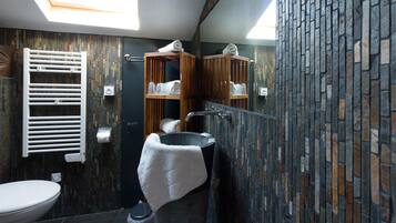A modern bathroom with a skylight, a freestanding bathtub, a towel rack, and a mirror.