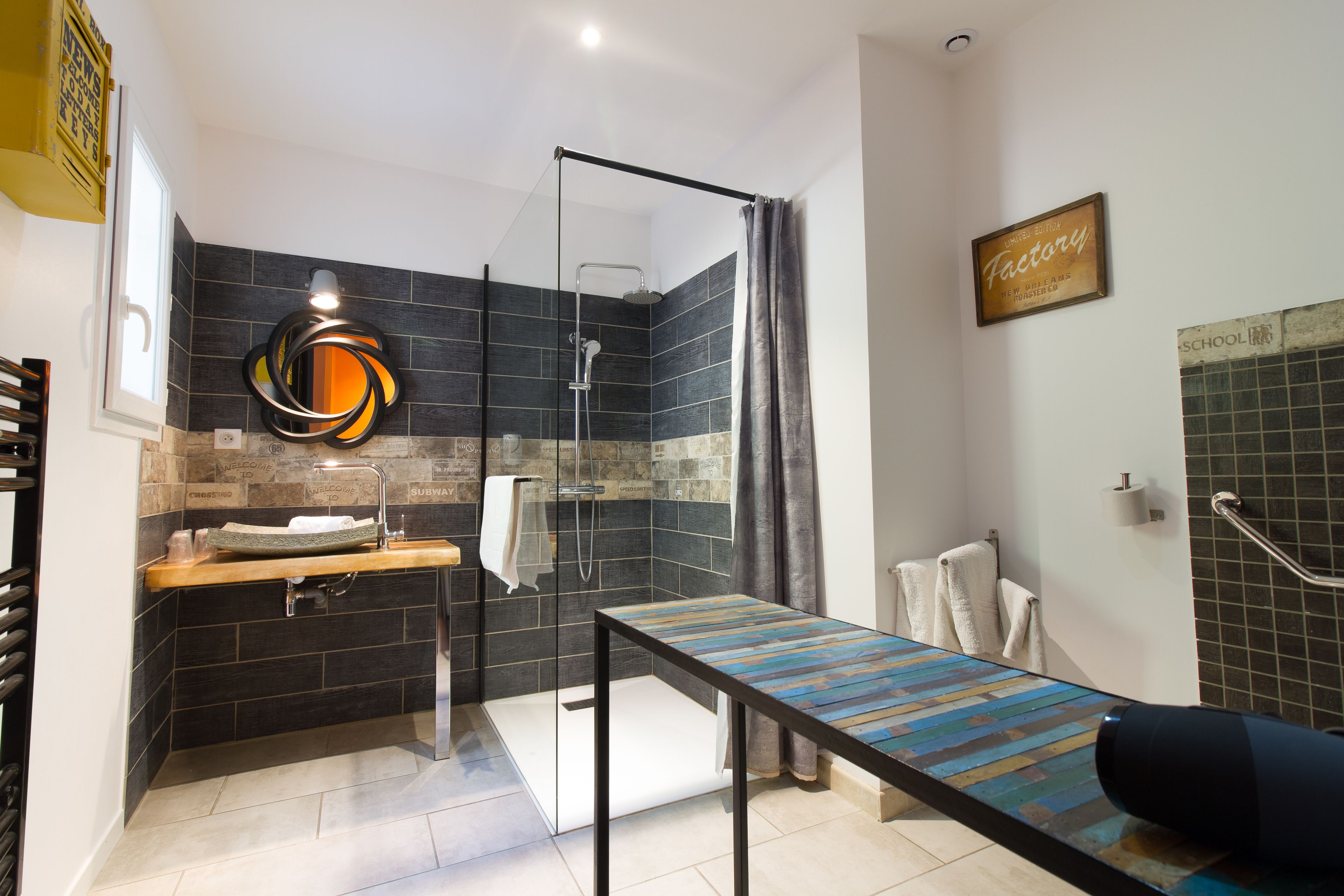 A modern bathroom with a glass shower enclosure, a wooden vanity, and a bench.