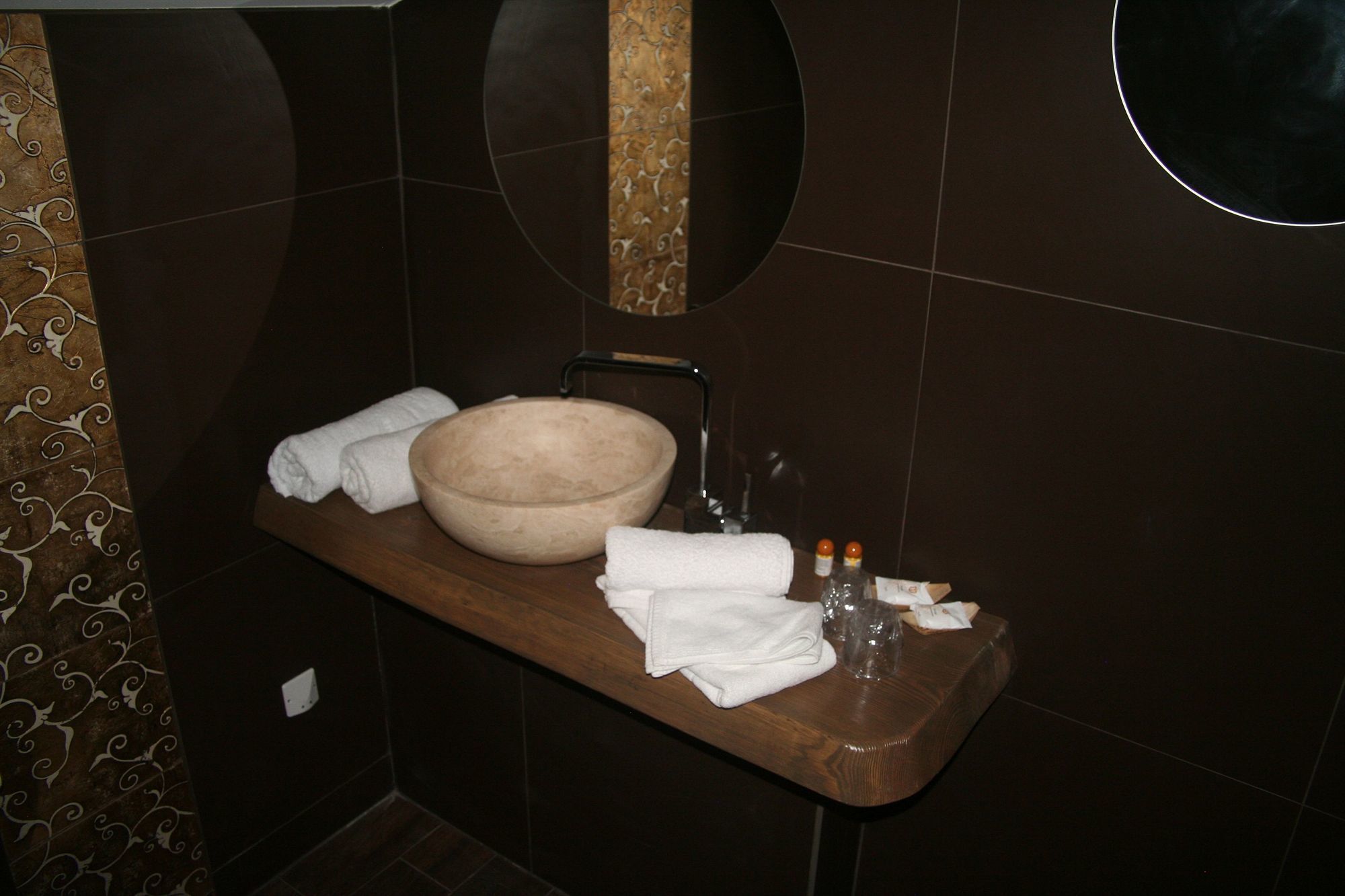 Une salle de bain avec un meuble-lavabo en bois, un grand lavabo en forme de coupe, deux serviettes blanches et un flacon de savon pour les mains.