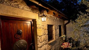 A stone building with a wooden door, a small window, and a stone planter with flowers.
