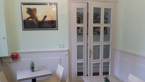 A room with a white door, a framed picture on the wall, and a small table with a potted plant. - Hôtel de la Cathédrale (Reims)