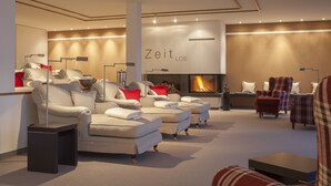 A modern lounge area with sofas, armchairs, and a fireplace. - Schüle's Gesundheitsresort & Spa - Erwachsenenhotel (Oberstdorf)