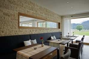 Un restaurant avec un mur en pierre, des tables en bois et une vue sur les montagnes.