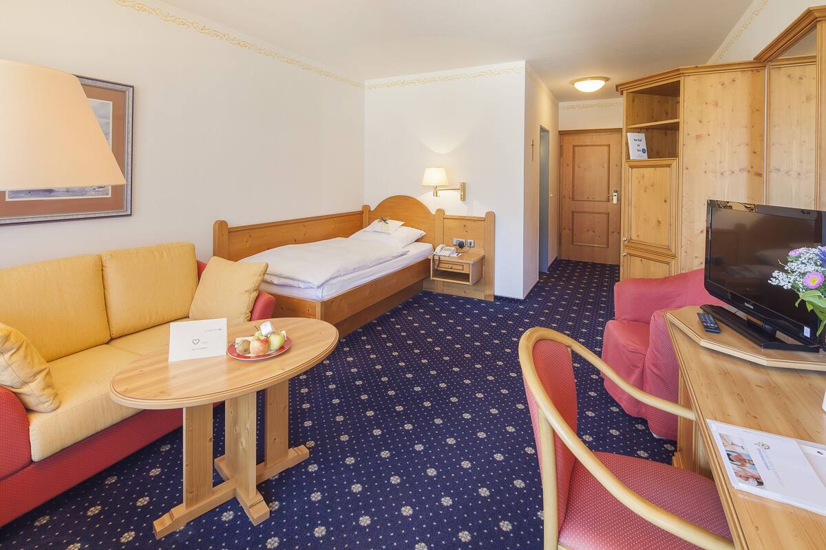 Ein Hotelzimmer mit Bett, einer Couch, einem kleinen Tisch, einem Fernseher und einem Schreibtisch mit Stuhl.