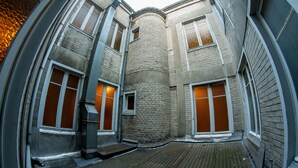 Esquina de un edificio con una columna de ladrillo, grandes ventanales y una terraza de madera.