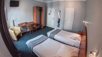 Ein Hotelzimmer mit zwei Betten, einem Schreibtisch, einem Stuhl und einem Kleiderschrank.