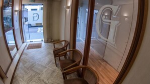 Un vestíbulo de hotel con una recepción, un muro de cristal con un logotipo y suelo de madera.