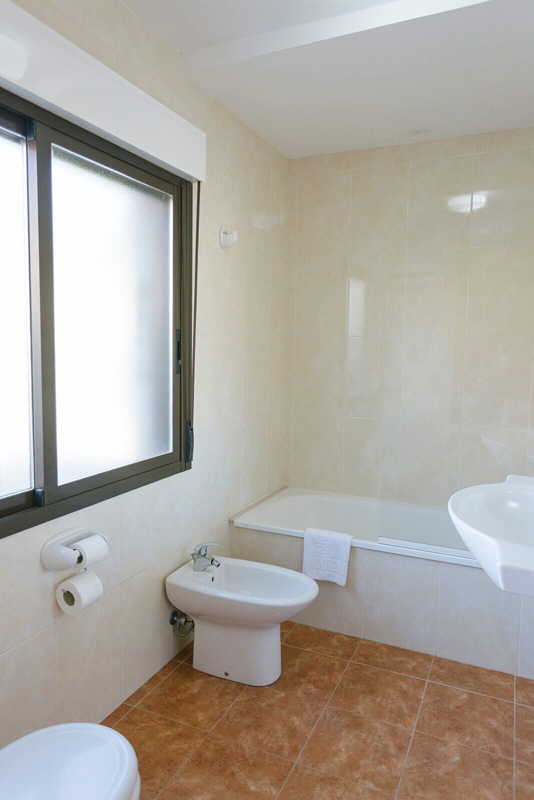 A bathroom with a toilet, bidet, bathtub, and sink.