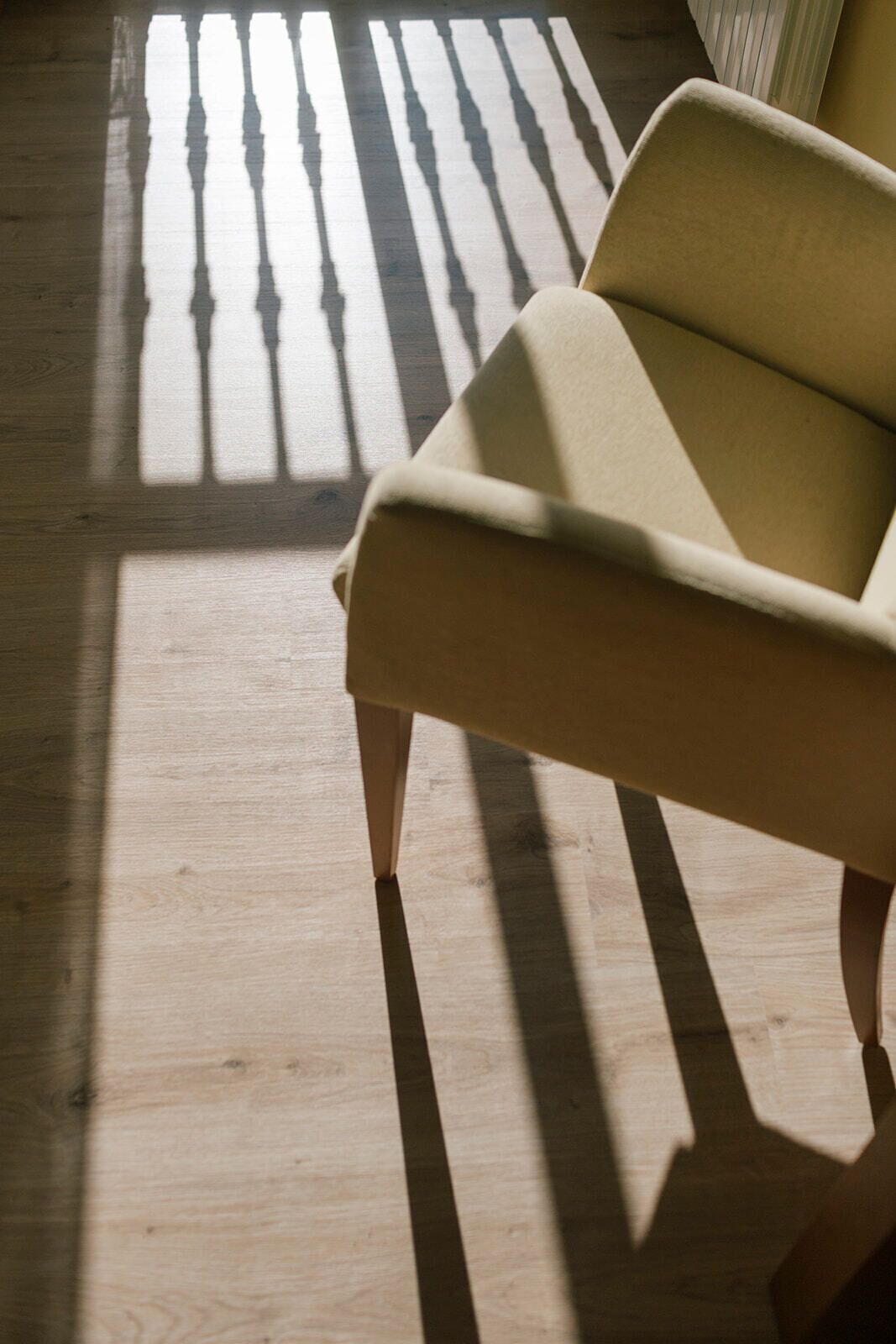 Un pavimento in legno con un divano chiaro in primo piano.