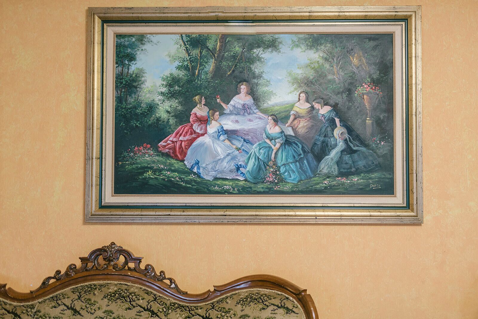 Un cuadro enmarco que muestra a un grupo de personas en un jardín.