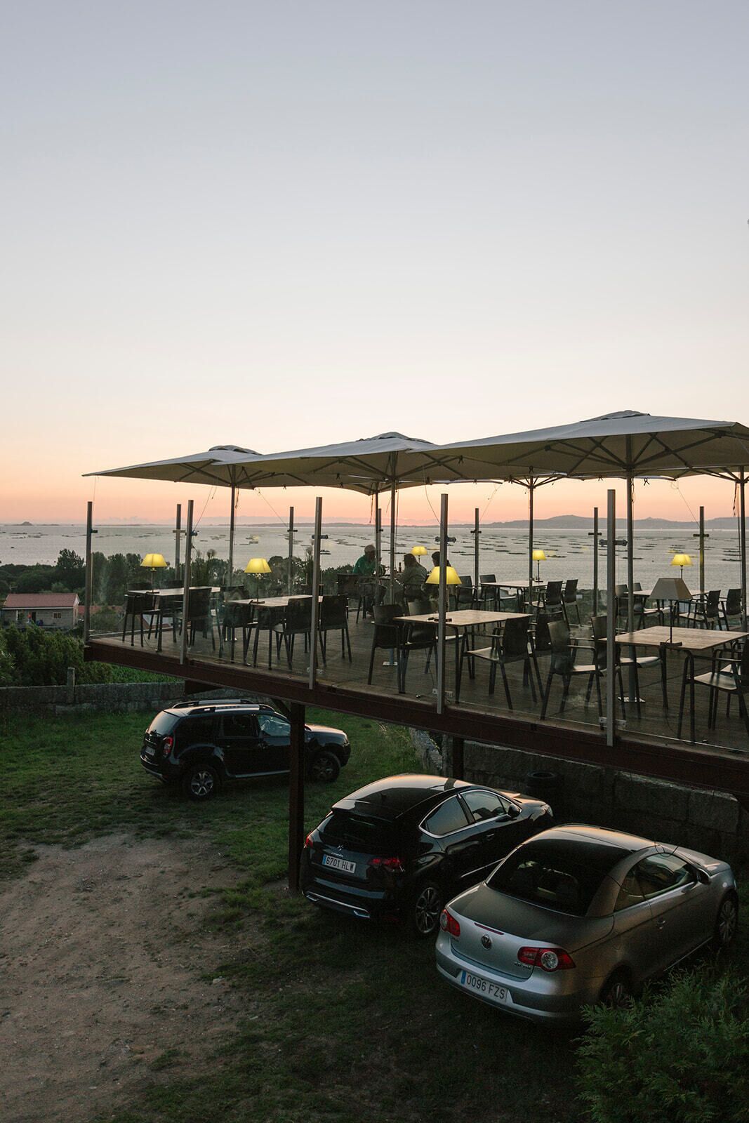 Un espace extérieur aménagé avec des parasols, des tables et des chaises, offrant une vue sur une étendue d’eau.