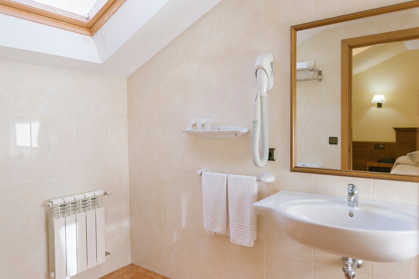 A modern bathroom with a white sink, a mirror, a towel rack, and a hairdryer.