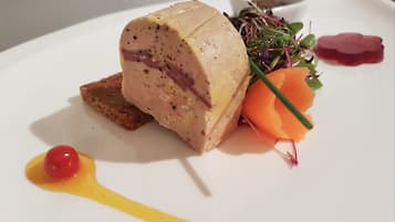 En tallerken med kødret, en lille skål med grønt, en gulerodsskive og en klat sauce.