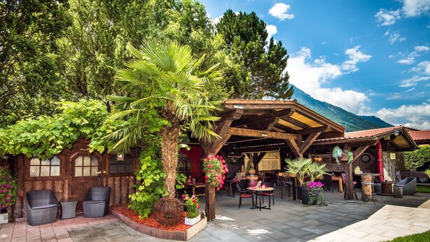 A rustic outdoor seating area with wicker chairs, a wooden pergola, and potted plants. - Rêves Gourmands (Vernayaz)