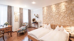 A hotel room with a large bed, a desk, a chair, and a stone wall. - Hotel Roter Turm (Solothurn)