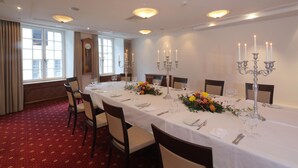 A formal dining room with a long table set for a meal, surrounded by chairs, and decorated with flowers and candelabras. - Hotel Roter Turm (Solothurn)
