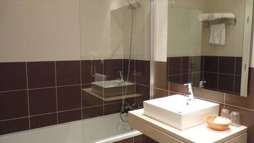 A modern bathroom with a glass-enclosed shower, a white sink, and a mirror above it.