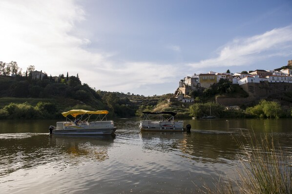 Une rivière avec des bateaux et une colline avec des bâtiments.
