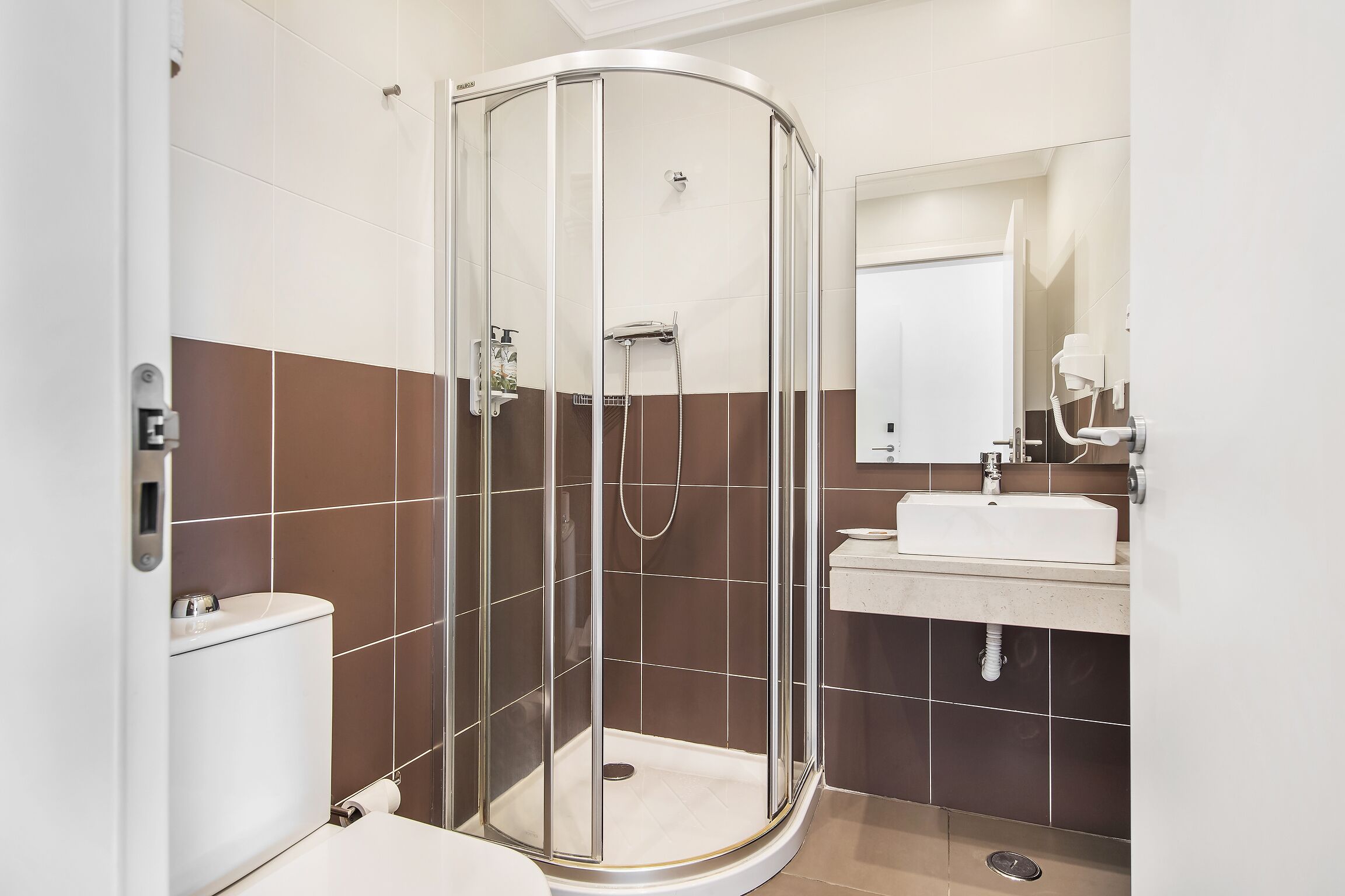 Ein modernes Badezimmer mit einer Duschkabine, einer Toilette und einem Waschbecken mit Spiegel.