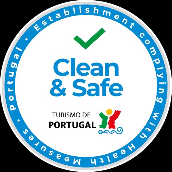 A circular logo with the text "Clean & Safe" and "Turismo de Portugal" along with a checkmark and a graphic of three people. - Hotel Museu (Mertola)